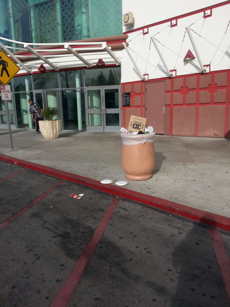 An overflowing trash can outside of the AMC Promenade 16.