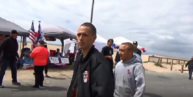 A screenshot showing Hammerskin Nation skinheads at the event. Notice the distinctive crossed hammers on the leading man's jacket.