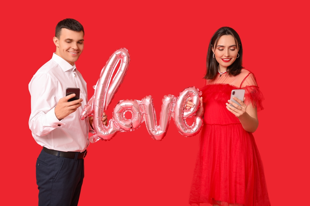 Young,Couple,With,Mobile,Phones,And,Air,Balloon,In,Shape